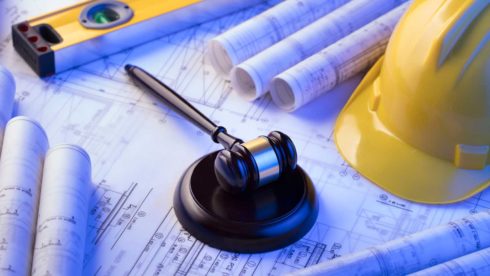 blue prints, hard hat and gavel on table