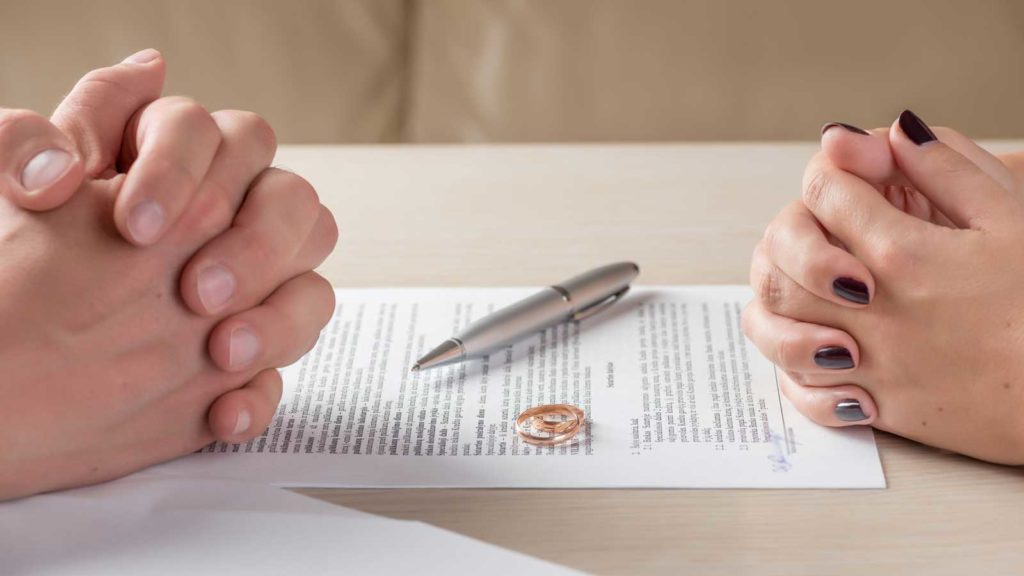 man and woman with wedding rings and contract sitting on table