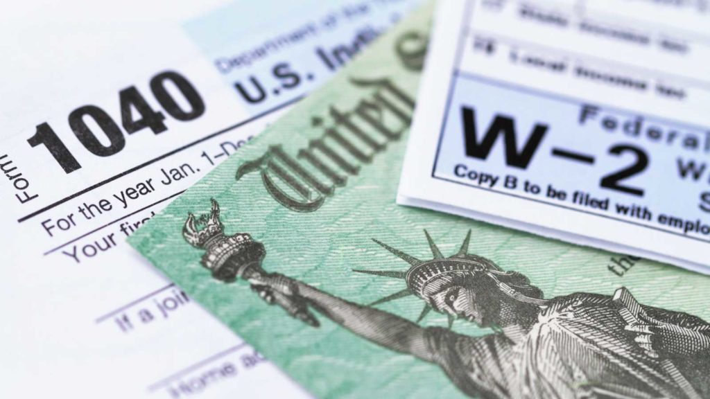 government check with W-2 and 1040 forms on table